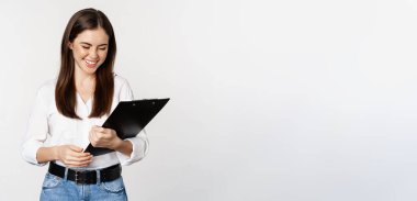Portrait of corporate woman holding clipboard at work, standing in formal outfit over white background.