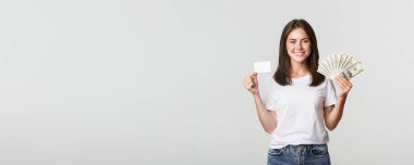 Heyecanlı gülümseyen kızın portresi. Elinde para ve kredi kartı var..