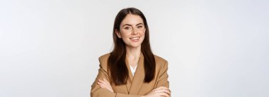 Portrait of confident businesswoman in suit, cross arms on chest, looking like real professional, smiling happy and assertive, white background.