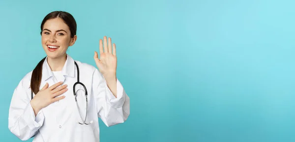 Дружелюбная Улыбающаяся Женщина Доктор Поднимает Руку Называет Себя Представляя Стоя — стоковое фото