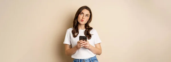 Portrait Woman Thinking Holding Mobile Phone Looking Thoughtful Face Standing — Stockfoto