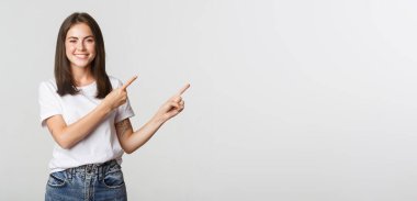 Çekici, gülümseyen esmer kız parmaklarını sağ üst köşeye doğru gösteriyor, logo gösteriyor..