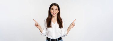 Happy smiling adult woman pointing sideways, showing two choices, products on sale logo or diagram, standing over white background.