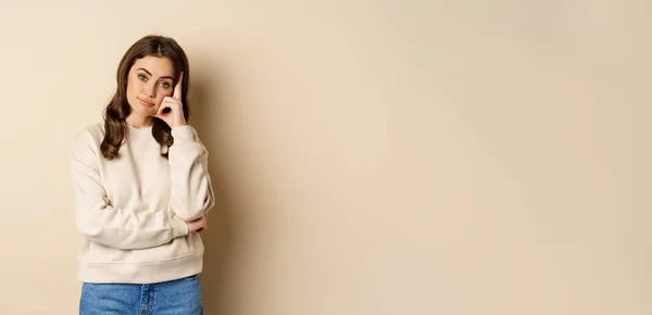 Stock image Annoyed woman, roll eyes and looking unamused, bothered and bored, standing over beige background.