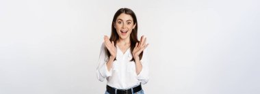 Enthusiastic laughing woman, smiling amused, clapping hands, applausing, standing in formal outfit over white background.