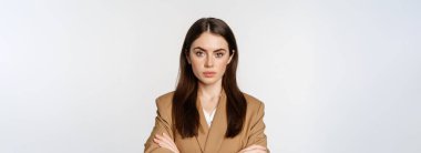 Portrait of confident businesswoman in suit, cross arms on chest, looking like real professional, smiling happy and assertive, white background.