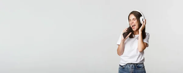 Atrakcyjna Szczęśliwa Kobieta Gra Aplikację Karaoke Śpiewa Smartfona Nosi Słuchawki — Zdjęcie stockowe