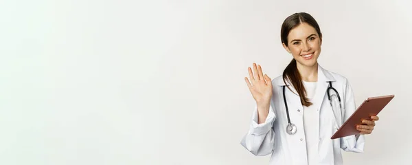 Amistosa Doctora Médico Saludando Con Mano Sosteniendo Tableta Digital Sonriendo — Foto de Stock