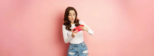 Happy Beautiful Girl Playing Mobile Video Game Holding Smartphone Horizontally — стоковое фото