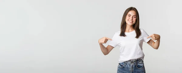 Atrakcyjny Uśmiech Brunetka Dziewczyna Wskazując Swoje Logo Pokazując Baner Środku — Zdjęcie stockowe