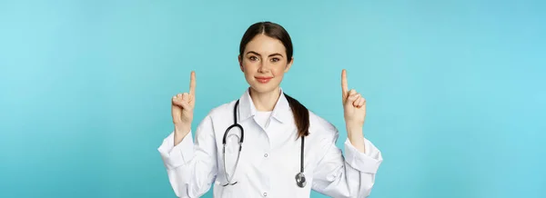 Portrait Confident Young Woman Doctor Medical Worker Coat Pointing Fingers — стоковое фото