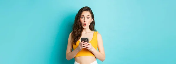 Parece Interesante Chica Bonita Intrigada Sosteniendo Teléfono Inteligente Mirando Emocionada —  Fotos de Stock