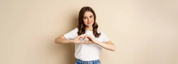 Lovely Woman Showing Heart Love Sign Smiling Standing Beige Background — Foto de Stock