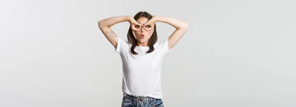 Pobavená Roztomilá Brunetka Dívka Vypadá Překvapeně Dělat Gesto Ruční Brýle — Stock fotografie