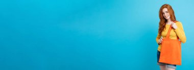 Alışveriş kavramı - turuncu alışveriş çantası ile gülümseyen portre genç güzel çekici Dişileştirilmiş kız yakından. Mavi Pastel renkli