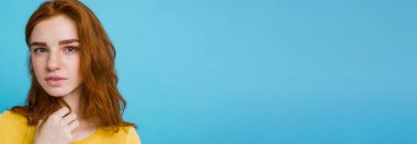 Kameraya gülümseyen kızıl saçlı mutlu kızıl saçlı kızın portresi. Pastel mavi arka plan. Boşluğu Kopyala.