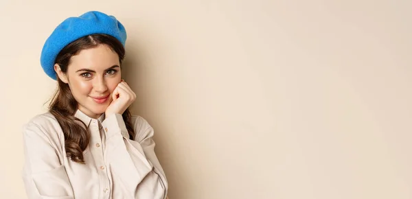 stock image Close up portrait of feminine young woman in trendy french hat, posing cute and romantic, making silly coquettish face and tender smile, beige background.