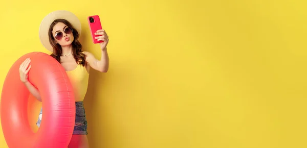 stock image Stylish brunette girl on vacation, taking selfie with swim ring, going on beach, swimming in sea on summer holiday, standing over yellow background.