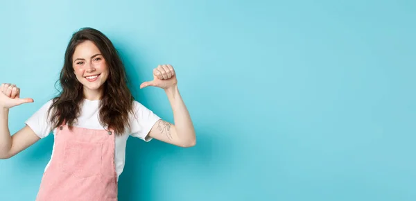 stock image Young smiling woman pointing at herself, looking confident and happy, self-promoting, talking about her, personal achievement, standing over blue background.