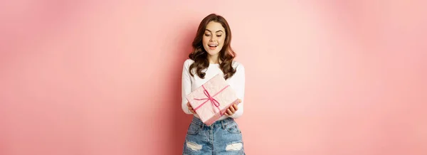 お祝いや休日 幸せな美しい女の子を保持ギフト プレゼントや笑顔包まれ ピンクの背景に立って 驚きを受け取る — ストック写真