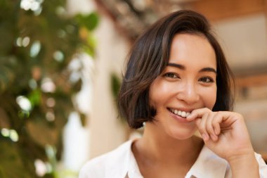 Güzel esmer Asyalı kız portresi, kameraya gülümseyen ve flört eden, kıkırdayan şirin. Boşluğu kopyala