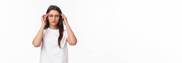 Waist-up portrait of attractive young woman trying get ready, massaging temples with closed eyes as relaxing, ease the pain, thinking rational, put effort into making up plan, white background.