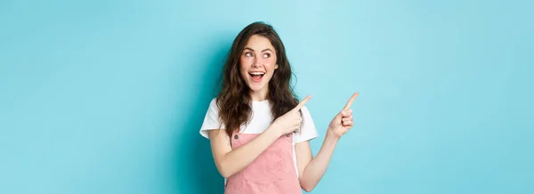幸せな笑顔の女性モデルの肖像画とともに魅力的な赤面 指差し指左とプロモーションの提供を見て 広告コピースペースを示す 青の背景 — ストック写真