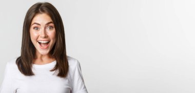 Neşeli, güzel esmer kızın portresi. Eğleniyor, gülümsüyor. Heyecanlı ve şaşırmış görünüyor..