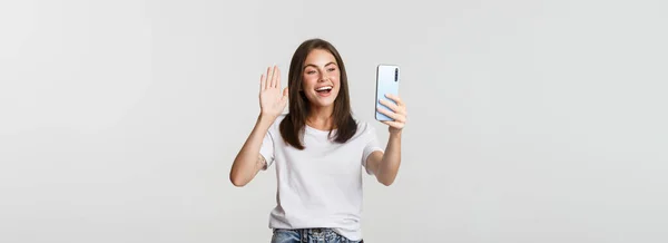 Φιλικό Ελκυστικό Κορίτσι Λέει Γεια Χαιρετώντας Χέρι Στο Smartphone Κατά — Φωτογραφία Αρχείου