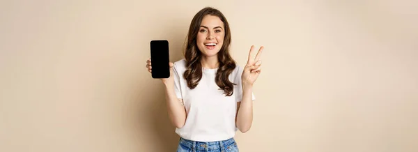 Portrait Attractitve Caucasian Woman Showing Mobile Phone Screen Peace Sign — 图库照片