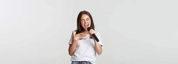 Carefree Όμορφο Κορίτσι Τραγούδι Καραόκε Κρατώντας Μικρόφωνο Στέκεται Λευκό Φόντο — Φωτογραφία Αρχείου