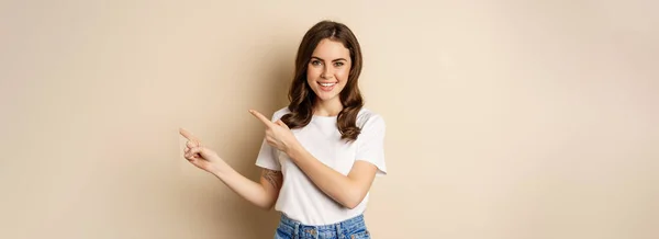 Smiling Brunette Woman Shirt Pointing Fingers Right Showing Promo Offer — Stockfoto