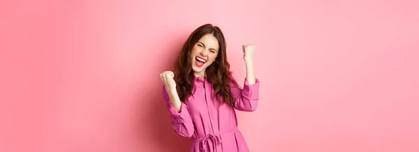 幸せと興奮した顔で美しい笑顔の女性悲鳴 拳ポンプを作る 優勝し チャンピオンのような感じ ピンクの背景の上に立って — ストック写真
