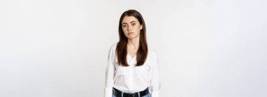 Sad and gloomy woman sulking, looking disappointed and moody, standing upset against white background.