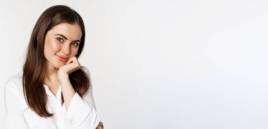 Close up of beautiful, coquettish brunette woman, blushing and smiling flirty, posing against white background. Copy space