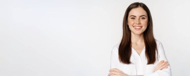 Close up of confident corporate woman, professional entrepreneur smiling, cross arms on chest and smiling enthusiastic, standing over white background.