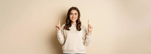 Enthusiastic Girl Pointing Fingers Showing Announcement Promo Text Logo Upwards — стоковое фото