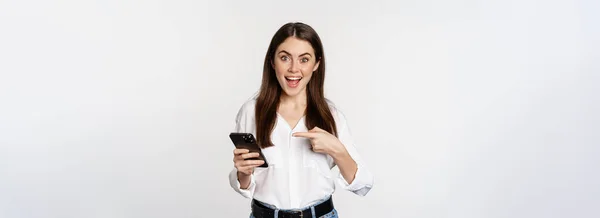 スマートフォンや笑顔で指を指している熱狂的な女の子は 携帯電話 白い背景にアプリを使用して オンラインで大規模な販売を示しています — ストック写真