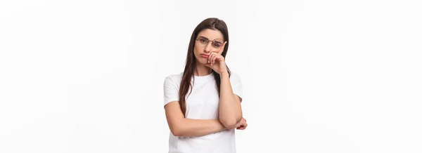 stock image Waist-up portrait of bored, uninterested young brunette female in glasses, feel tired or sleepy, listening to boring conversation, lean on hand look reluctant with lack of interest, white background.