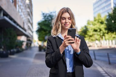 Gülümseyen genç bir satıcının portresi, iş kadını cep telefonuna mutlu bir yüzle bakıyor, akıllı telefondan mesaj okuyor..