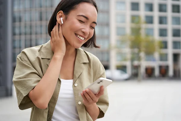 Sonriente Chica Asiática Escucha Música Los Auriculares Inalámbricos Mira Teléfono —  Fotos de Stock