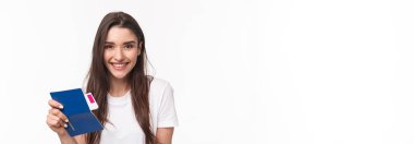 Seyahat, tatil, yaz konsepti. Yakın plan portre güzel uzun saçlı genç kadın, havaalanında oturan yolcu, elinde pasaport ve uçak bileti, tatile gidiyor, beyaz arka plan.