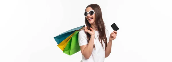 休闲和生活方式的概念 无忧无虑 快乐的年轻女性形象通过买新东西 用信用卡付账 把购物袋扛在肩上 面带微笑地回头看 缓解了压力 — 图库照片