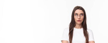 Sinirli, kibirli, gözlüklü güzel bir kadının yakın plan portresi. Sinir bozukluğundan gözleri yuvarlanan, aptal konuşmaları dinlemekten bıkmış, beyaz arka plan rahatsız olmuş..