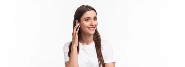 魅力的な笑顔若いブルネットの女性のクローズアップポートレートは 電話で話している 友人に連絡するために無線イヤフォンを使用して 離れて屈託のない ヘッドフォンで音楽を聞いて 白い背景 — ストック写真