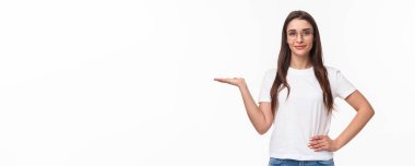 Gözlüklü hoş görünümlü beyaz bir kadının belden yukarı portresi, çekici bir kız birini elinde tutuyor, kollarını kaldırıyor, sanki bir ürünü varmış gibi, gülümseyen kamera, reklam, beyaz arka plan..