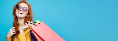 Alışveriş kavramı - portre genç güzel çekici Dişileştirilmiş kız kameraya alışveriş çantası ile seyir gülümseyen yakından. Mavi Pastel renkli. Kopya alanı