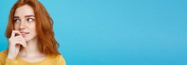 Kameraya gülümseyen kızıl saçlı mutlu kızıl saçlı kızın portresi. Pastel mavi arka plan. Boşluğu Kopyala