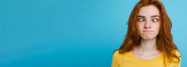 Komik surat kameraya bakarak mutlu Kızıl kızıl saçlı kızla headshot portresi. Pastel mavi arka plan. Kopya alanı.