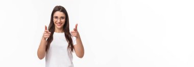 Kendinden emin, arsız, gözlüklü ve tişörtlü, sinsi sinsi parmaklarıyla kamerayı, parmak tabancalarını işaret eden, ekibine ya da ekibine katılacak kişiyi seçen,.